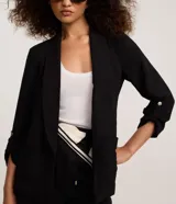 Blazer negro de sastrería confeccionado en tejido airflow con textura arrugada, cuello con solapa, bolsillos delanteros y mangas 3/4 con martingalas en los puños.