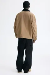 Pantalón cargo de lona de algodón con bolsillos laterales con solapa, bolsillos al bies y bolsillos traseros. Presenta pliegues en las rodillas y cierre con botón.