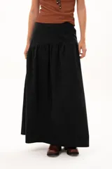 Pollera larga de color negro con corte a la cadera y detalle de frunce que aporta volumen y movimiento a la prenda. Confeccionada en tela suave con acabado tipo piel de durazno.