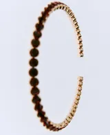 Collar rígido abierto de metal dorado con cristales incrustados en tono oscuro.