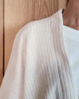 Ruana abierta de tejido de punto acanalado en color beige, con diseño holgado y caída fluida.