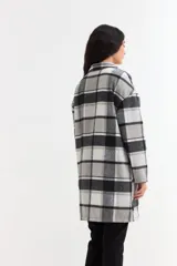 Tapado liviano de paño con diseño de cuadros en tonos gris, blanco y negro. Presenta cuello solapa, cierre frontal con botones y bolsillos laterales.