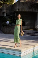 Top corto de color verde lima con diseño calado de motivos circulares y abanicos. Presenta cuello a la caja, sin mangas y un corte recto tipo crop top.