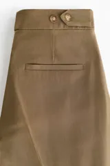 Pantalón de tiro alto de sarga color verde militar, con corte holgado y diseño barrel. Presenta pinzas y pliegues en la parte delantera y trasera, bolsillos al bies y bolsillos traseros decorativos.