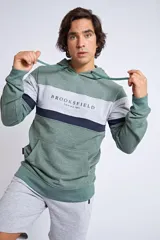 Canguro con capucha y cordón ajustable, de diseño color block en tonos verde, gris y azul marino. Presenta un bolsillo frontal tipo canguro y el logo de la marca bordado en el pecho.