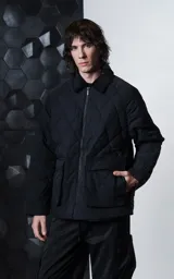 Campera oversize negra confeccionada en microfibra opaca con diseño matelaseado de rombos, cuello de corderoy, cierre frontal metálico y amplios bolsillos delanteros con solapa y broche snap.