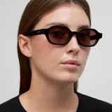 Lentes de sol con armazón de acetato negro y forma ovalada angular. Poseen cristales polarizados en tono marrón con protección UV400.