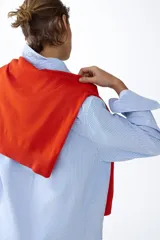 Camisa de corte relajado con diseño a rayas finas en tonos celeste y blanco, cuello clásico, mangas largas con puños anchos abotonados y bajo redondeado.