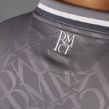 Camiseta de fútbol Adidas del Real Madrid, modelo Tercer Uniforme. Diseño gris con cuello polo, logo de Adidas y escudo del club en blanco. Estampado frontal con el sponsor Emirates Fly Better.