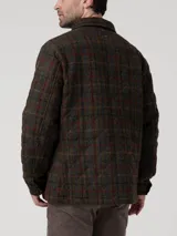 Chaqueta de lana Harris Tweed con patrón de tartán en tonos verdes, marrones y detalles en burdeos. Presenta cuello camisero, cierre frontal con botones, bolsillos de parche y acolchado interior térmico.