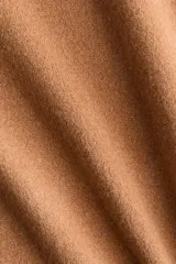 Buzo de punto fino en color tostado, con cuello en V acanalado y mangas largas con puños elastizados.