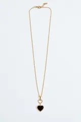Collar dorado de cadena fina con un dije doble en forma de corazón, compuesto por un corazón pequeño hueco y un corazón grande esmaltado en negro con borde dorado.