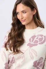 Buzo tejido en jacquard con estampado floral en tonos azul y marrón sobre base color crema. Presenta cuello redondo y puños acanalados.