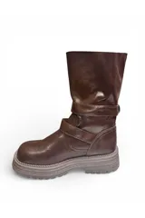 Bota alta de cuero marrón con suela track gruesa, detalles de hebillas metálicas en el empeine y botones decorativos en la caña.