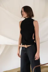 Remera negra de tejido de punto con cuello alto y sisas amplias. Presenta aberturas laterales a la altura de la cintura.