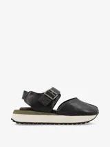 Sandalia de cuero color negro, con tira ancha sobre el empeine con hebilla metálica ajustable, talón cubierto y plataforma con base de goma blanca y suela dentada.