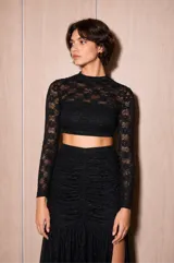 Top de encaje negro con mangas largas, cuello alto y diseño ceñido al cuerpo con transparencias.