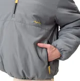 Buzo tipo anorak de la marca Rusty, color gris verdoso, con medio cierre frontal y bolsillos laterales. Presenta logo bordado en amarillo en el pecho, puños elásticos y ajuste en la parte inferior.