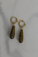 Aros tipo argolla con dije colgante en forma de gota de piedra natural en tonos marrones. Fabricados en acero quirúrgico dorado.