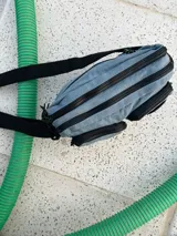 Bandolera azul de nylon con correa negra ajustable.