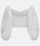 Blusa corta blanca de algodón con escote cuadrado, manga larga abullonada con bordados, y látex en la espalda.