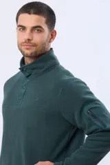 Buzo de abrigo confeccionado en tejido polar térmico, con cuello alto y cierre frontal parcial con broches. Presenta bolsillos laterales con cierre y un bolsillo adicional con cierre en la manga izquierda.