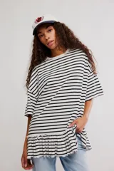 Remera oversize de punto rayada en blanco y negro, con cuello redondo, mangas cortas amplias y detalle de volado fruncido en el ruedo.