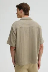 Camisa color caqui de manga corta con cuello resort y tapeta con botones. Tejido de punto waffle con corte holgado.