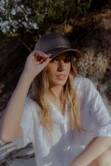 Gorra de béisbol negra de cuero sintético con hebilla metálica ajustable en la parte posterior.