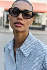 Camisa de cuello solapa y manga larga con puños abotonados. Presenta un diseño de rayas verticales azules y blancas con un estampado floral lineal superpuesto. Cierre frontal con botones.