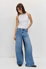 Jean wide leg de tiro medio, confeccionado en denim azul con detalles de paneles laterales en un tono más oscuro, tiro medio, cierre frontal con botón y cremallera, y diseño de perneras amplias.