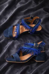 Sandalias de cuero gamuzado color azul, con taco ancho y tiras cruzadas en el empeine decoradas con flecos de cuentas. Cuentan con pulsera regulable al tobillo con hebilla metálica.