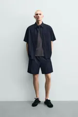 Bermuda relaxed fit de color azul marino confeccionada en tejido fluido con mezcla de viscosa, cintura elástica con cordón interior y bolsillos frontales.