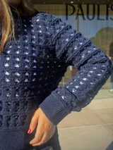 Chaqueta de punto calado color azul marino, con cierre frontal completo, cuello alto y puños tejidos en punto elástico.