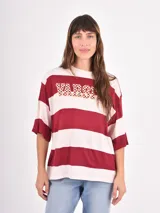 Remera de corte holgado con diseño de rayas horizontales anchas en tonos azul y blanco, cuello redondo y mangas cortas.