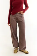 Pantalón de jean de tiro bajo, color marrón con efecto lavado, de corte recto y holgado. Presenta cordones de ajuste en los tobillos para modificar la silueta y bolsillos laterales.