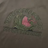 Remera de algodón color marrón topo, con cuello redondo, manga corta y pequeño estampado gráfico en el pecho izquierdo.