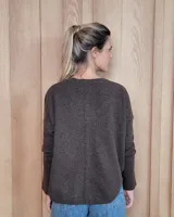 Sweater de punto color beige, con cuello en V, manga larga con puños acanalados y diseño holgado.