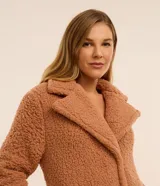 Bata de baño larga marca Lov, confeccionada en tejido sherpa color tostado, con cuello solapa, mangas largas y cierre de botón a presión.