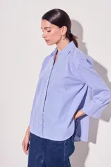 Camisa celeste con rayas verticales blancas, de corte clásico, con cuello camisero y mangas largas.
