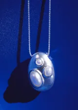 Collar largo plateado con cadena fina y dije esférico con apliques de cristal.
