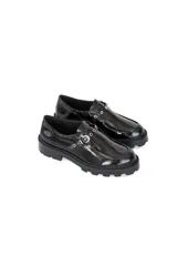 Mocasín de plataforma estilo track, confeccionado en cuero vacuno con acabado charol brillante. Presenta una puntera redondeada, suela robusta antideslizante y un detalle de tira con apliques metálicos en el empeine.