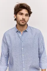 Camisa de manga larga de lino con diseño a rayas en tonos celestes y blancos, cuello camisero clásico y cierre frontal de botones.