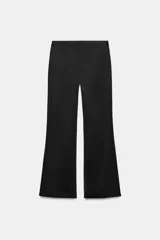 Pantalón flare de tiro alto confeccionado en tejido satinado color negro, con bajo en línea evasé y cierre frontal con cremallera oculta y gancho metálico.