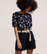 Short recto de cintura alta color crudo, confeccionado en viscolino, con trabillas en la cintura, pliegues y cierre tradicional. Incluye cinturón de rafia artificial con hebillas de argollas.