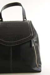 Mochila de cuero vacuno marrón con acabado pulido, solapa en forma de V y costuras decorativas. Cuenta con cremalleras laterales y asas ajustables.