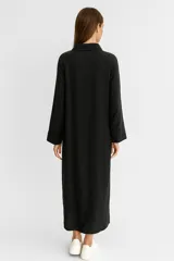 Vestido camisero blanco de lino, corte holgado, largo midi, con cuello camisero, abotonadura frontal y mangas 3/4 con puños. Incluye un bolsillo de parche en el pecho y aberturas laterales en el ruedo.