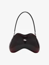 Bolso de hombro para mujer de Diesel, con forma orgánica y estructura rígida, acabado brillante con efecto degradado de negro a rojo oscuro. Posee un asa de hombro negra y un pequeño logo metálico plateado en el centro.