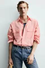 Camisa de corte relajado color celeste, confeccionada en mezcla de algodón y seda. Presenta cuello solapa, cierre frontal de botones, manga larga con puños abotonados y dos bolsillos de plastrón con solapa en el pecho.