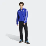 Campera deportiva Adidas de la Selección Argentina, color azul con las icónicas tres tiras blancas en las mangas. Presenta cuello alto, cierre frontal, logo del Trifolio bordado en el pecho y escudo de la AFA.